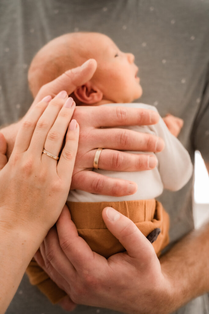 Foto Baby auf Arm mit haltenden Händen der Eltern, © A-Line-Photography Aylin Trautter